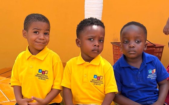 Three young BrightSteps students in school polos sitting together on a garden bench